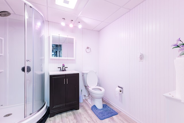 bathroom with vanity, wood walls, wood-type flooring, toilet, and a shower with door