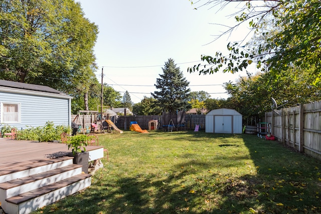 view of yard with a playground, a wooden deck, and a storage unit