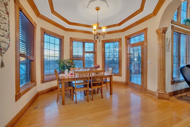 dining room with light wood-type flooring, crown molding, ornate columns, and a tray ceiling