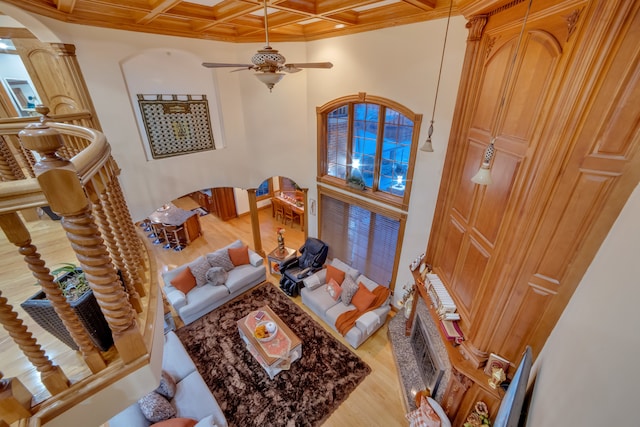 living room with coffered ceiling, light wood-type flooring, beam ceiling, ceiling fan, and ornamental molding