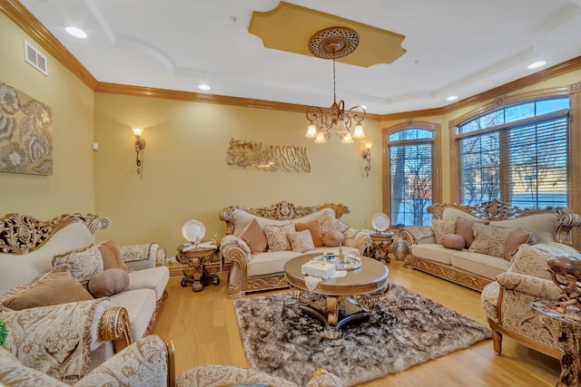 living room with hardwood / wood-style flooring, a tray ceiling, crown molding, and a notable chandelier