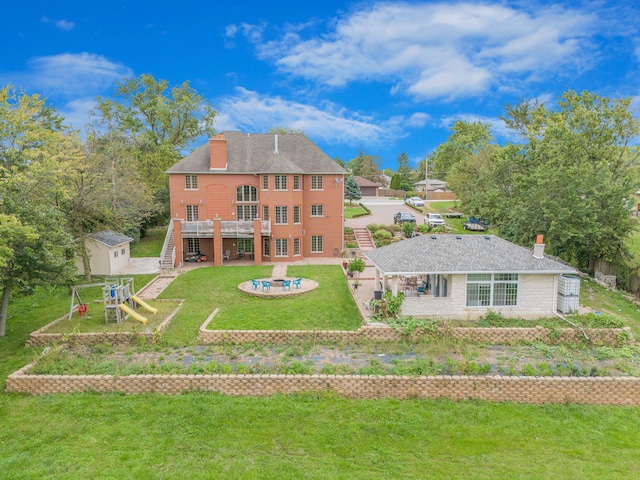 back of house featuring a patio area, an outdoor fire pit, a storage shed, a playground, and a yard