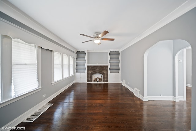 unfurnished living room with crown molding, ceiling fan, a brick fireplace, and dark hardwood / wood-style flooring