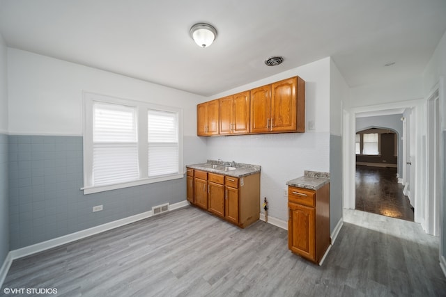 kitchen featuring light hardwood / wood-style flooring, sink, and tile walls