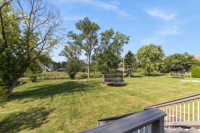 view of yard featuring a trampoline and a wooden deck