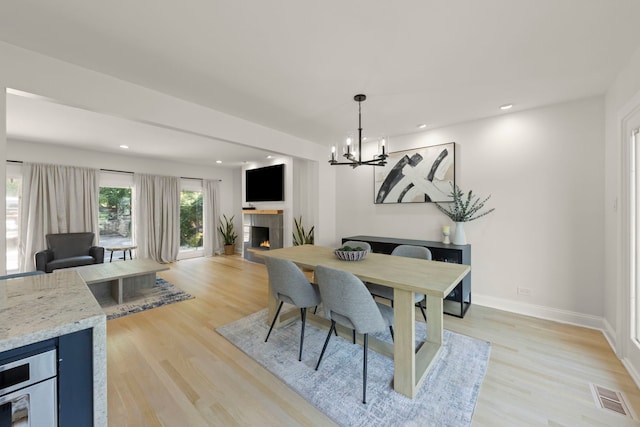 dining room with light hardwood / wood-style flooring, a fireplace, and a chandelier