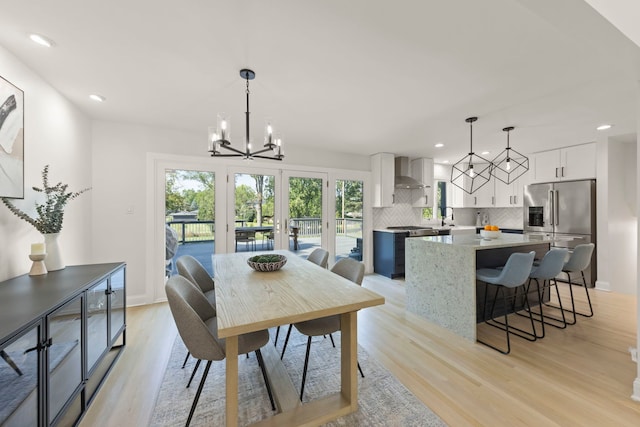 dining room with light wood-type flooring, a chandelier, and sink