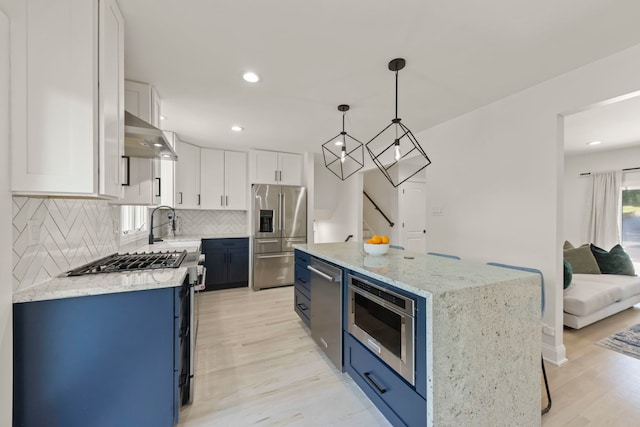 kitchen with a kitchen island, hanging light fixtures, white cabinetry, and premium appliances