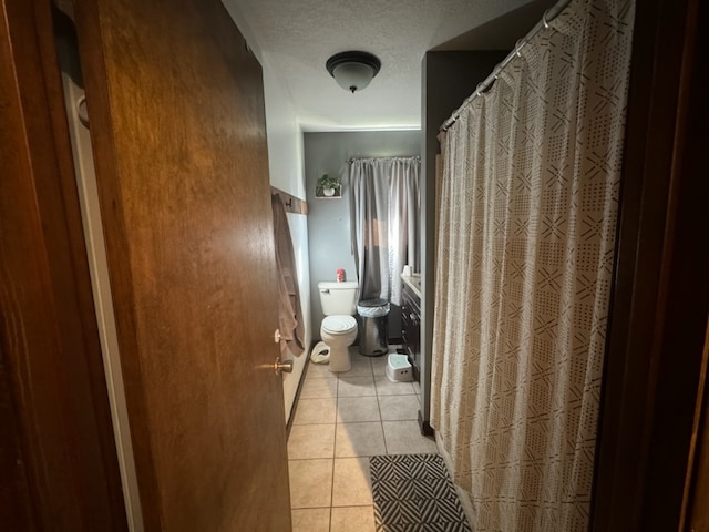 bathroom featuring a shower with curtain, a textured ceiling, toilet, and tile patterned floors