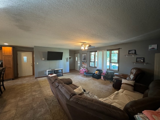 living room with ceiling fan, a textured ceiling, and tile patterned flooring