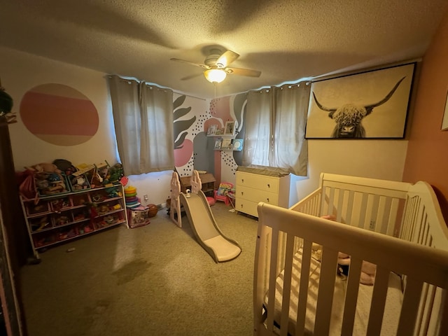 bedroom featuring carpet, ceiling fan, a nursery area, and a textured ceiling