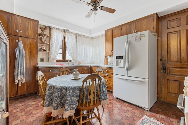 kitchen featuring ceiling fan, white refrigerator with ice dispenser, and sink