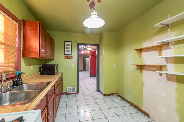 kitchen featuring light tile patterned floors, stove, pendant lighting, sink, and ceiling fan