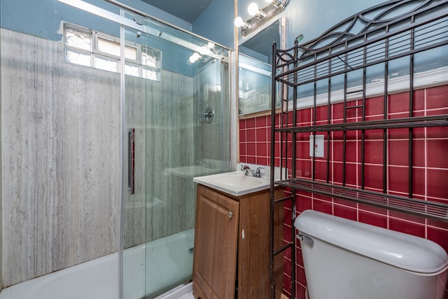 bathroom with walk in shower, vanity, toilet, and tile walls