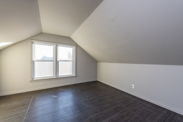 additional living space featuring dark wood-type flooring and lofted ceiling