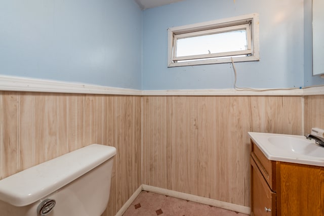 bathroom with vanity, wooden walls, and toilet