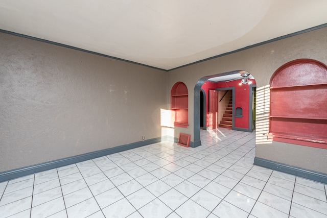 tiled empty room featuring ceiling fan and crown molding