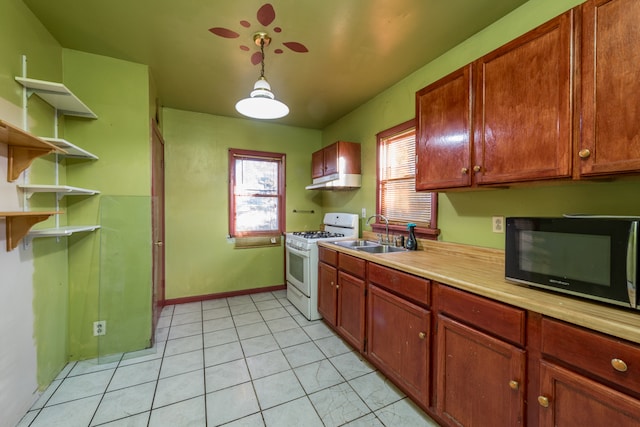 kitchen featuring white gas range, sink, decorative light fixtures, and light tile patterned flooring