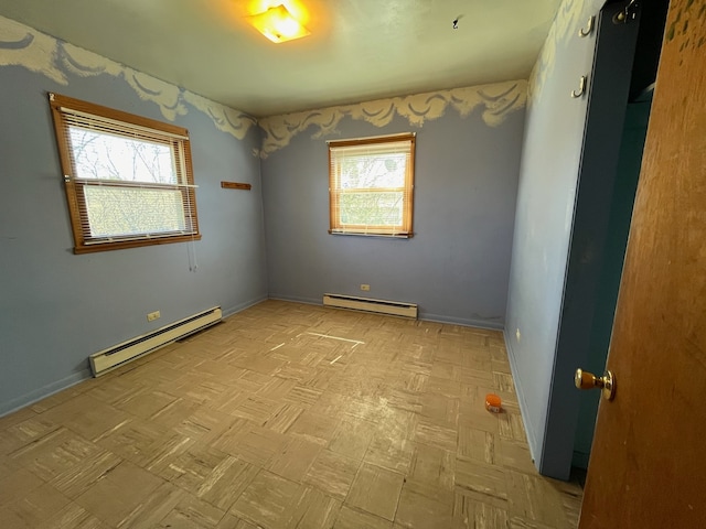 unfurnished room with baseboard heating, light parquet flooring, and a wealth of natural light