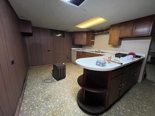 kitchen featuring wooden walls, kitchen peninsula, and sink