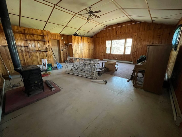 miscellaneous room with wood walls, vaulted ceiling, ceiling fan, and a wood stove