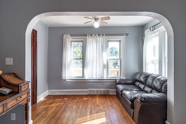 living area featuring ceiling fan, plenty of natural light, and dark hardwood / wood-style flooring