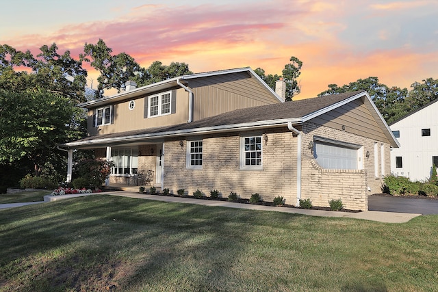 view of front of property with a garage, a yard, and covered porch