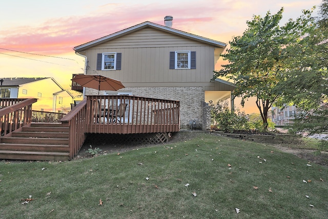 back house at dusk with a deck and a yard