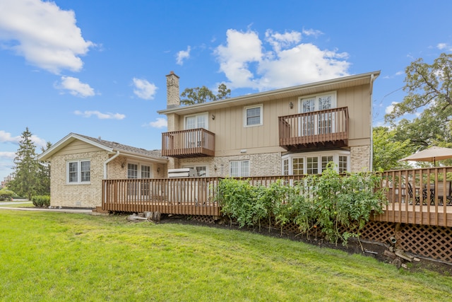 rear view of property with a lawn, a wooden deck, and a balcony