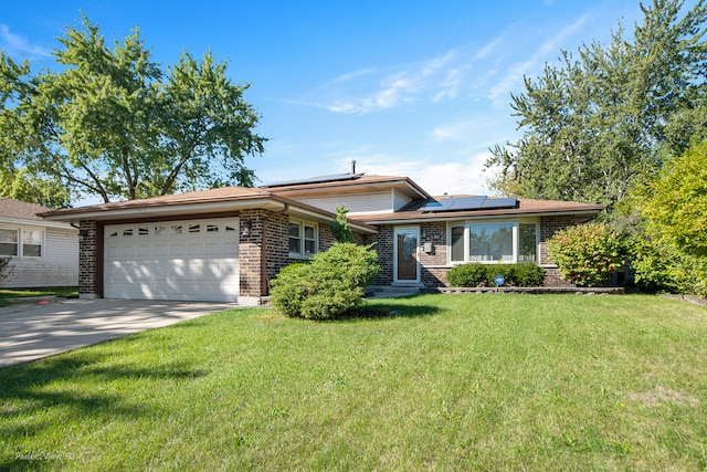 view of front of property with a front yard, solar panels, and a garage