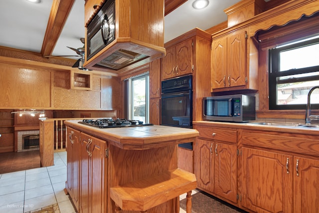 kitchen with appliances with stainless steel finishes, light tile patterned floors, tile counters, and a wealth of natural light