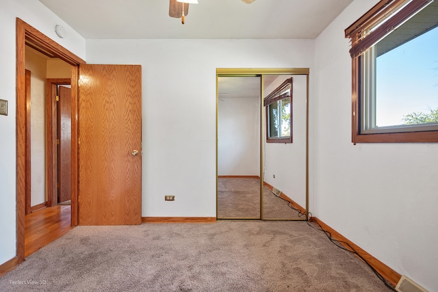 unfurnished bedroom with carpet flooring, a closet, and multiple windows