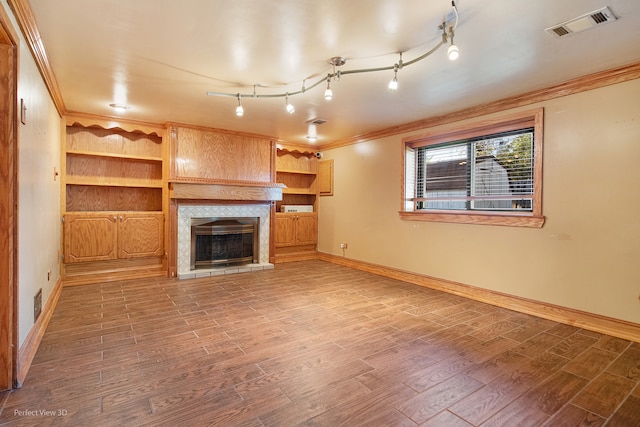 unfurnished living room featuring hardwood / wood-style floors, built in features, and ornamental molding