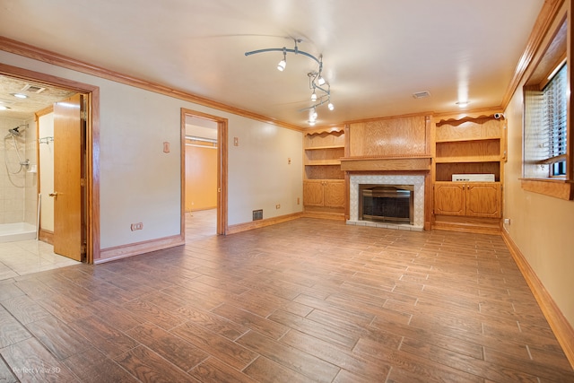 unfurnished living room with built in shelves, crown molding, and wood-type flooring