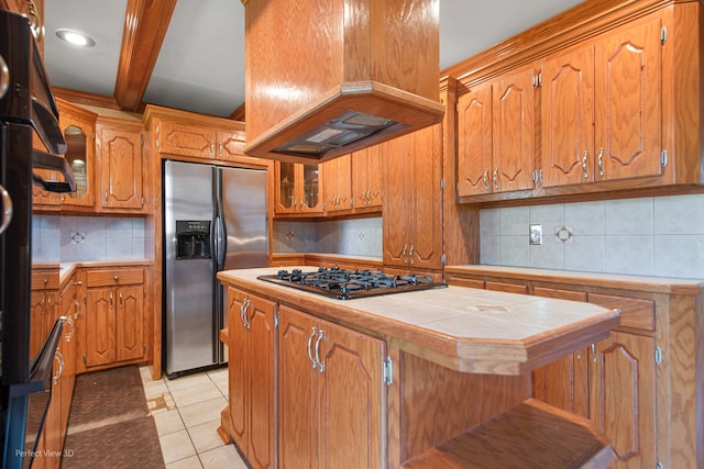 kitchen featuring custom exhaust hood, decorative backsplash, tile counters, light tile patterned flooring, and stainless steel appliances