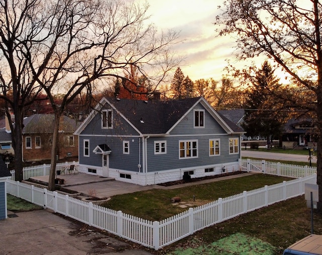 back house at dusk with a lawn and a patio area