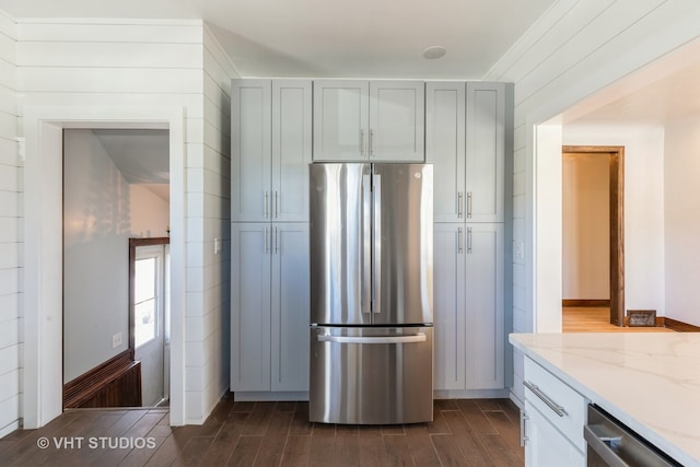 kitchen with light stone countertops, appliances with stainless steel finishes, ornamental molding, and dark wood-type flooring