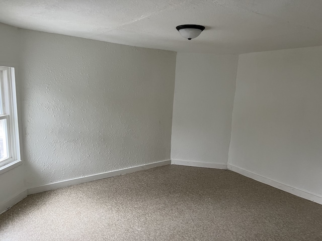 empty room with a textured ceiling and carpet flooring