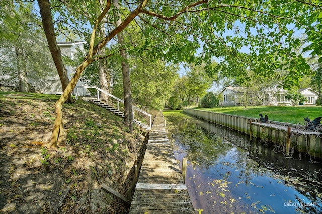 dock area with a water view and a yard