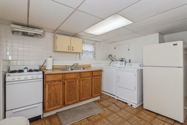 kitchen featuring light parquet floors, washing machine and dryer, white appliances, and sink