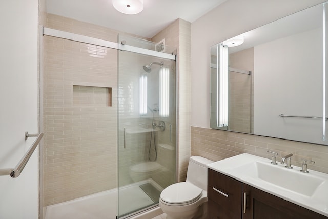 bathroom with vanity, tasteful backsplash, tile walls, toilet, and a shower with door