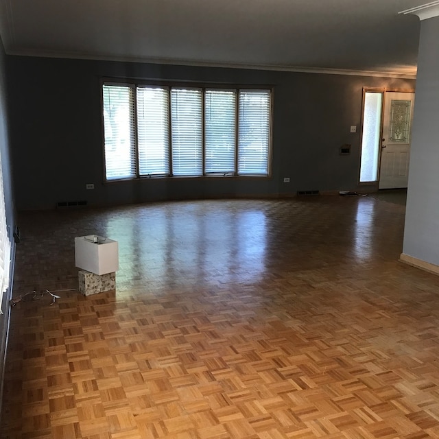 empty room featuring light parquet floors and crown molding