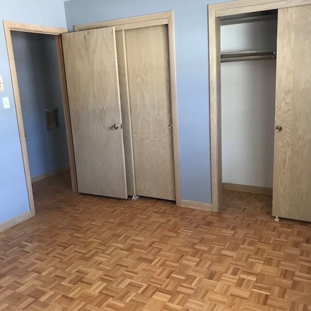 unfurnished bedroom with two closets and light parquet floors