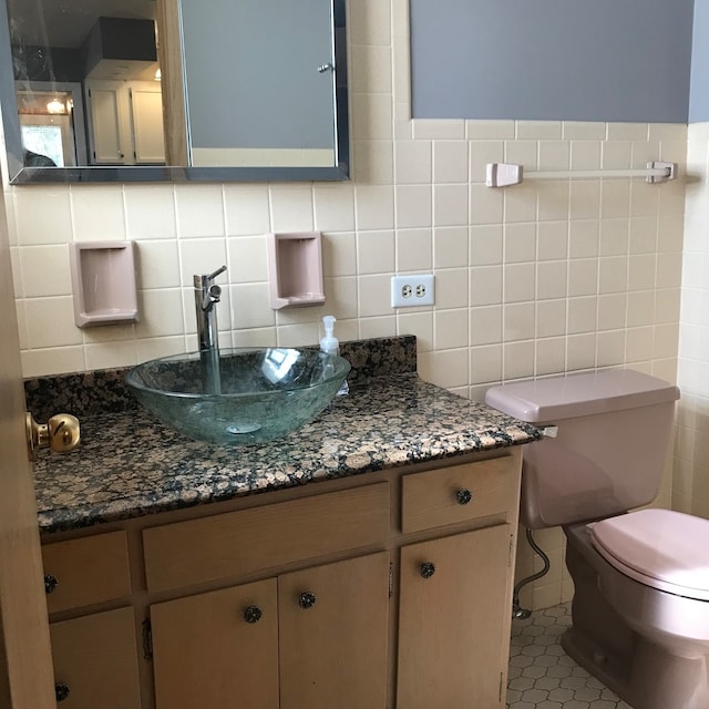 bathroom with tile walls, tile patterned floors, vanity, and toilet