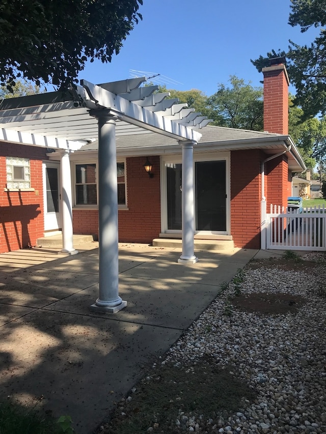 rear view of property featuring a pergola and a patio area