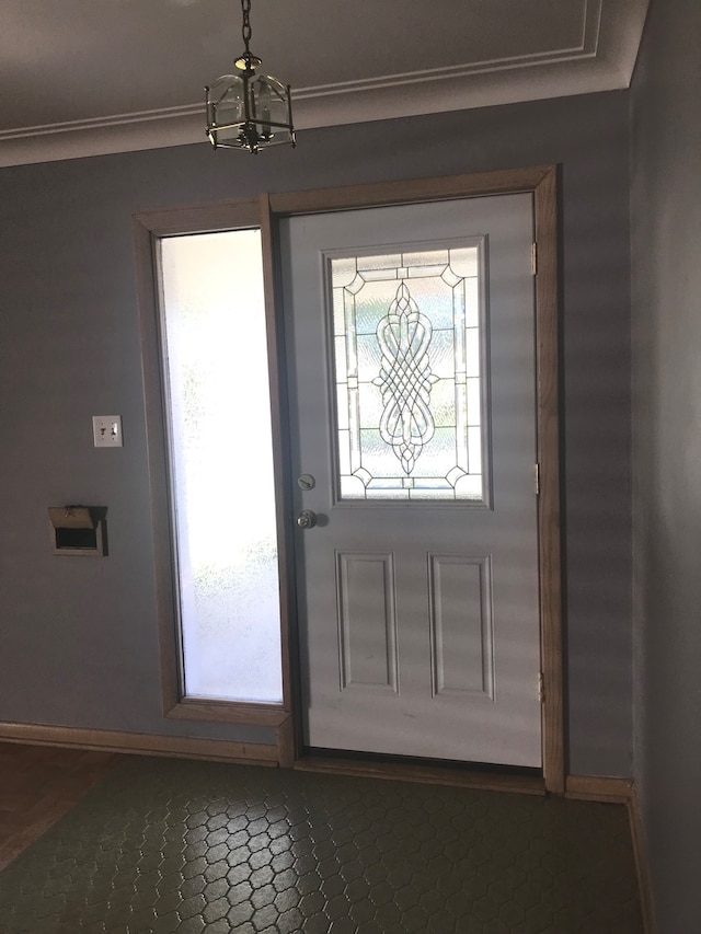 entryway with ornamental molding and a chandelier