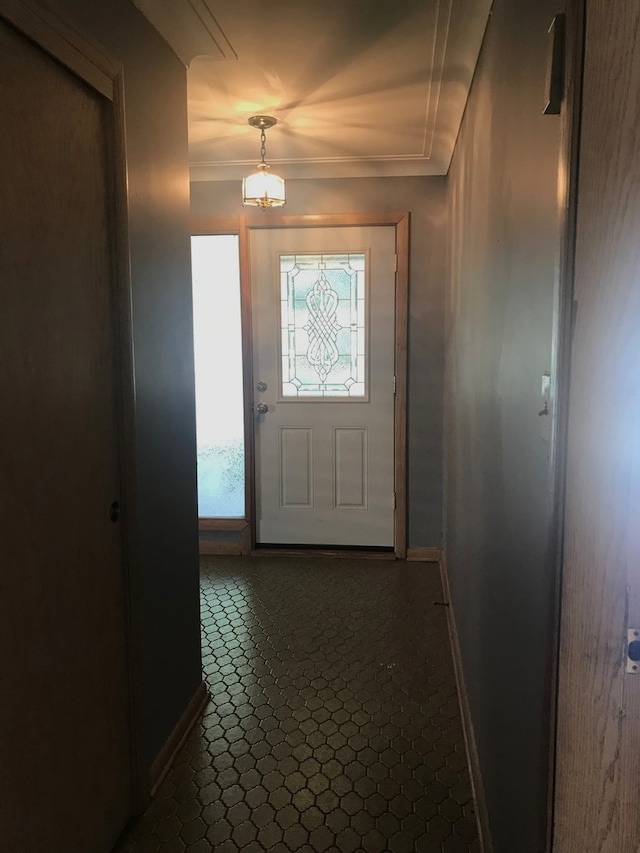 doorway to outside featuring ornamental molding and dark tile patterned floors