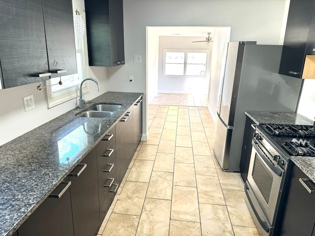 kitchen featuring dark stone counters, ceiling fan, gas range, and sink