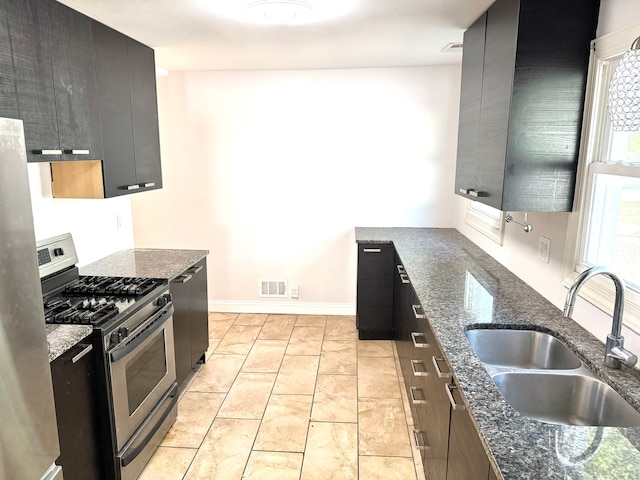 kitchen with dark stone countertops, appliances with stainless steel finishes, and sink