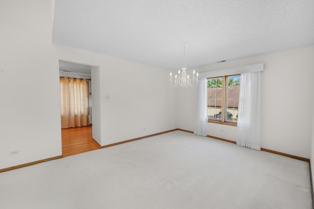 unfurnished room featuring light wood-type flooring, a chandelier, and a textured ceiling